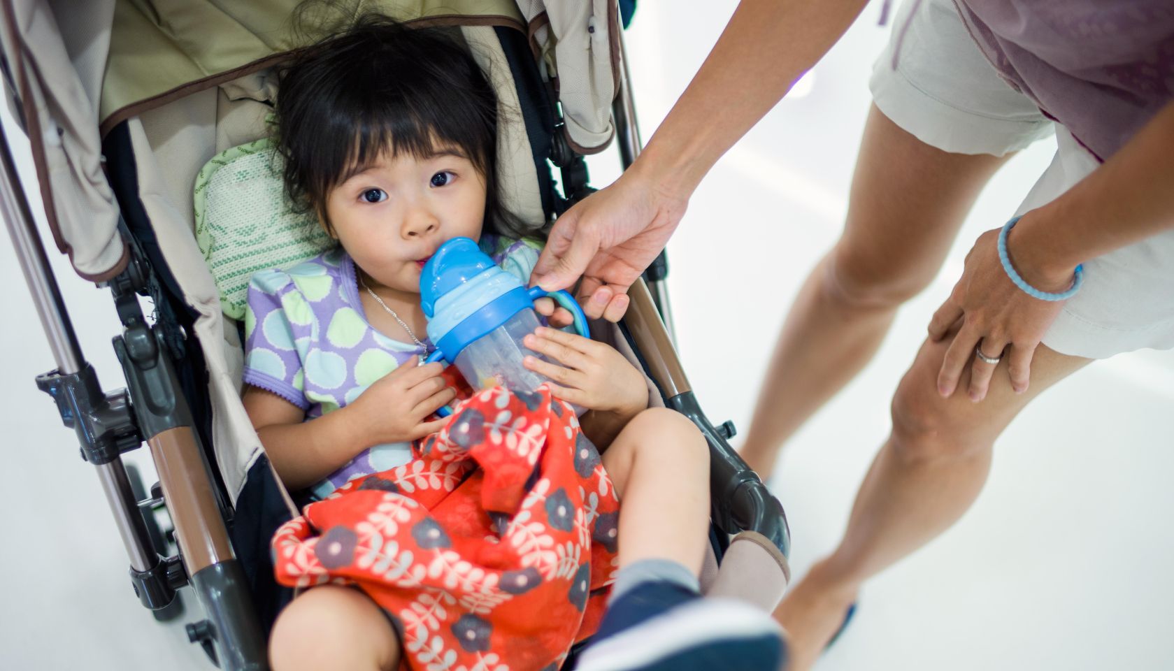 Toddler girl drinking water in stroller