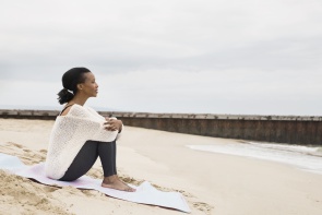 Serene woman sitting beach blanket looking at view