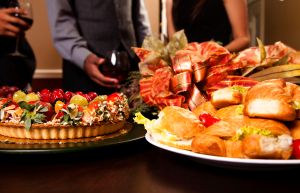 Friends sharing wine, food, appetizers. Holiday dining.