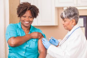 Doctor or nurse gives flu vaccine to patient at clinic.