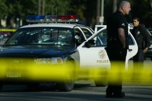 A bulletriddled LAPD patrol car sits disabled on St. Andrews Place and Venice Blvd Thursday morning