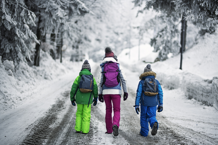 Kids with backpacks walking on winter road
