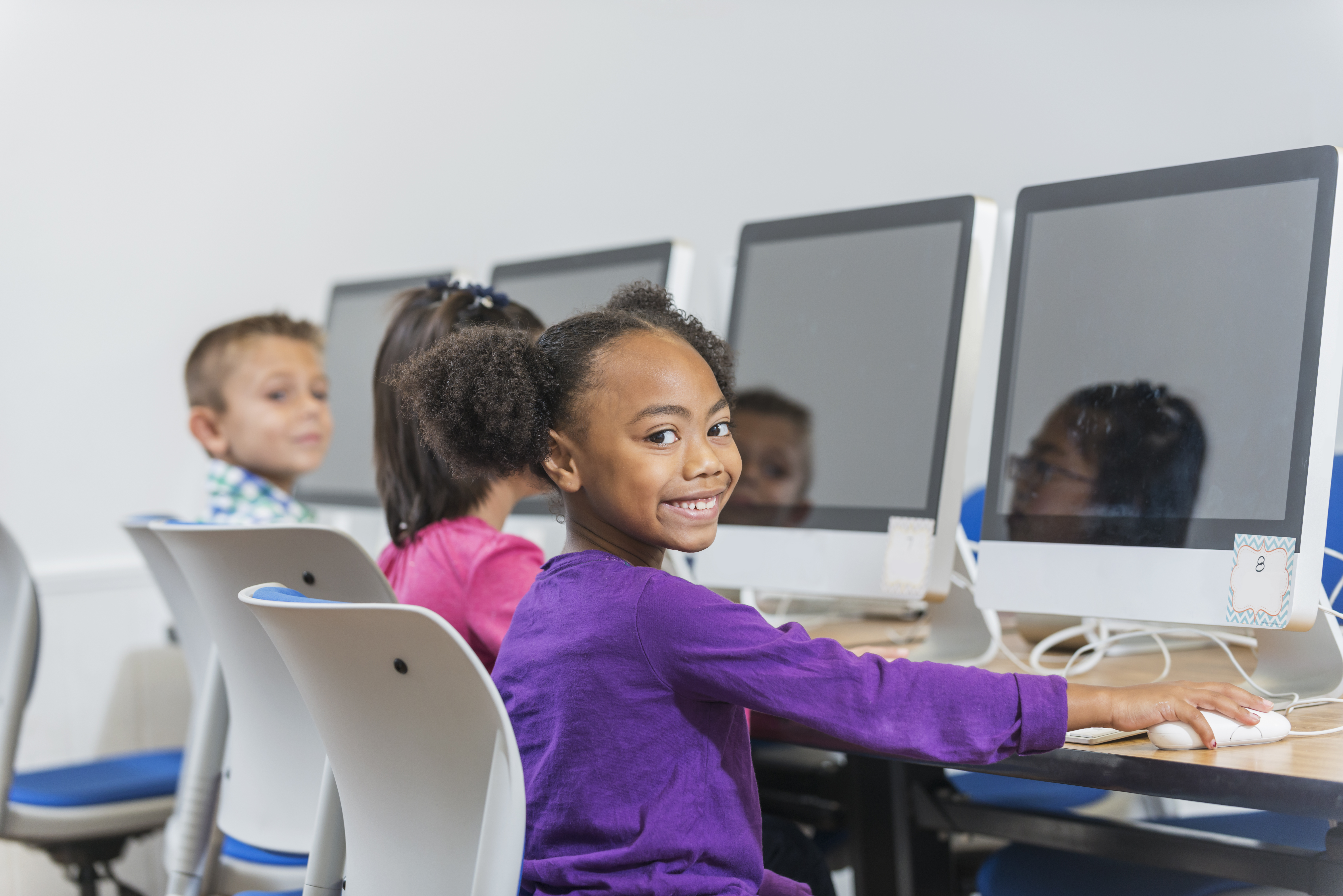 Black and Hispanic girl using computer in classroom