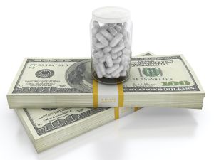 White pills on top of dollar bills bundle. High cost of healthcare concept