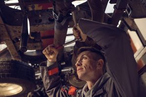 Mechanic using socket wrench while working on a chassis.