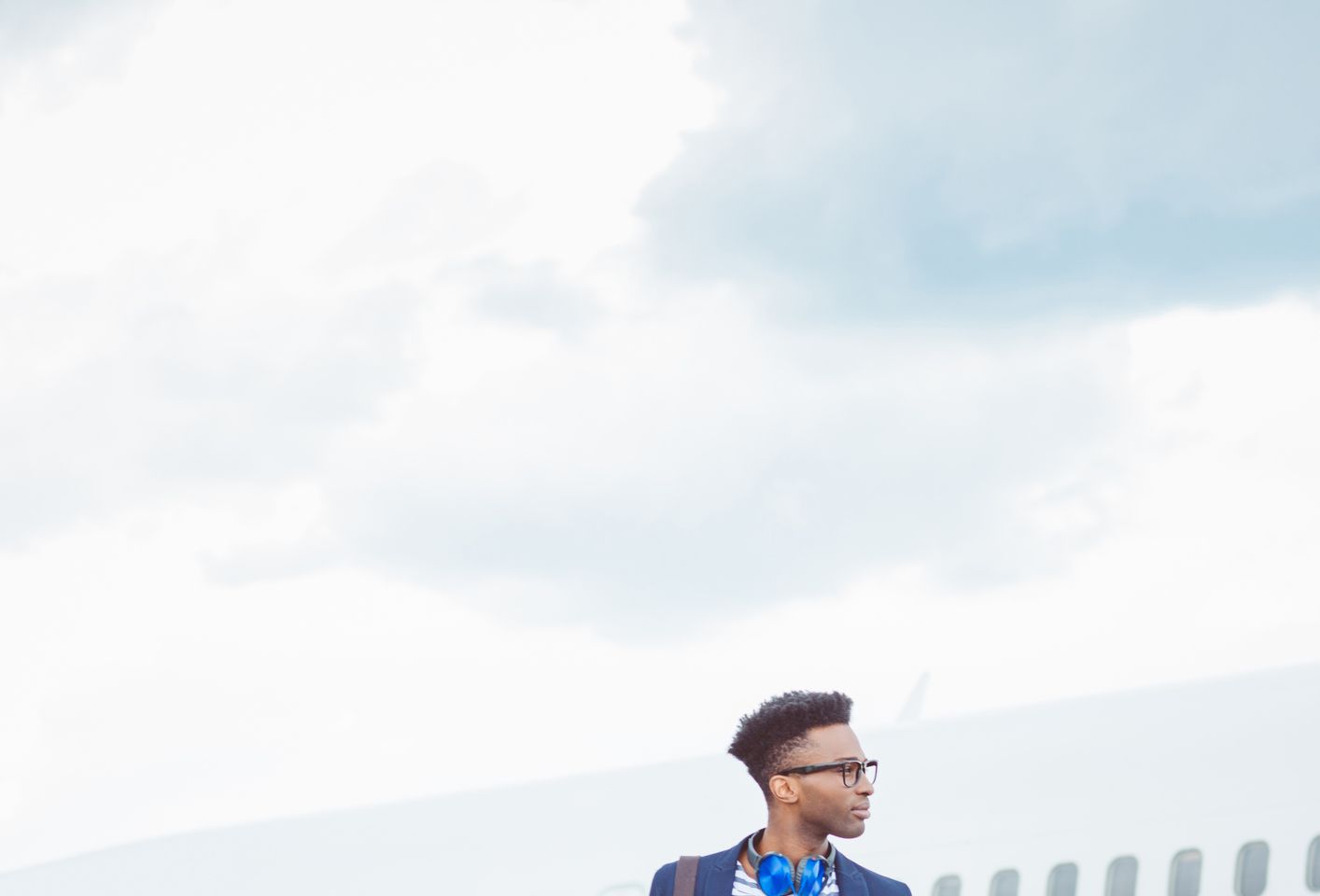 Young african businessman walking in front of airplane
