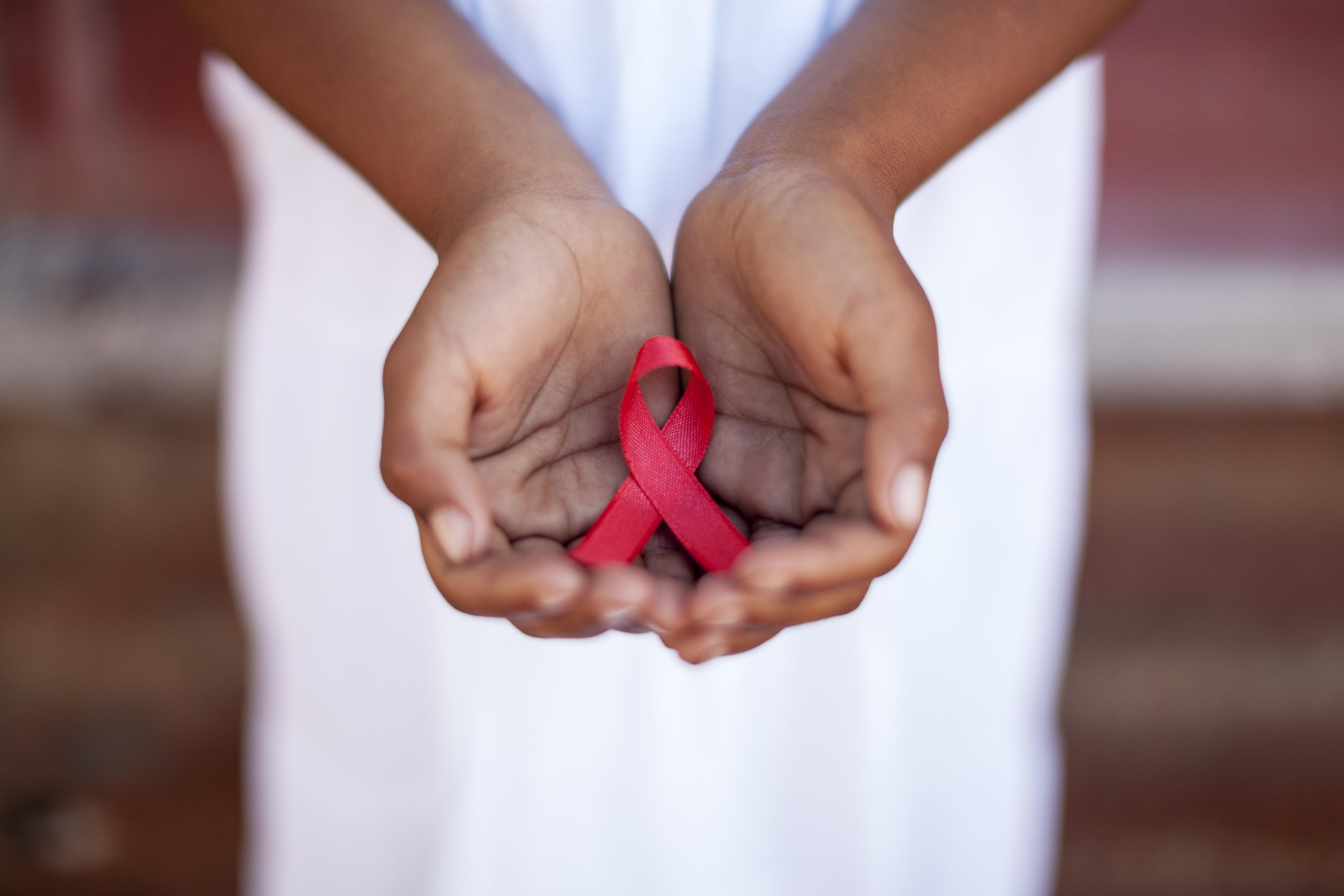 Child's hands holding an HIV awareness ribbon, Cape Town, South Africa