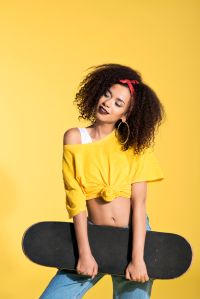Young afro woman holding skateboard