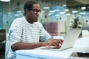 African Young Man Using Laptop in Office