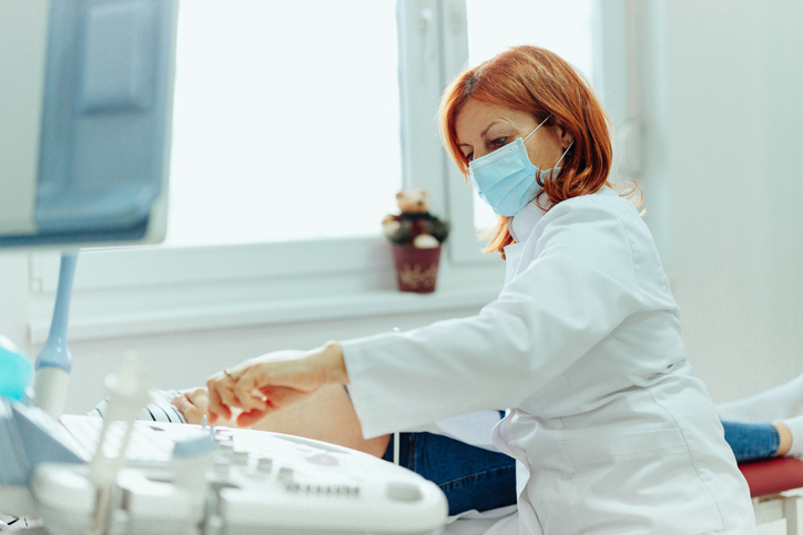Pregnant woman at ultrasound examination at doctor office during pandemic