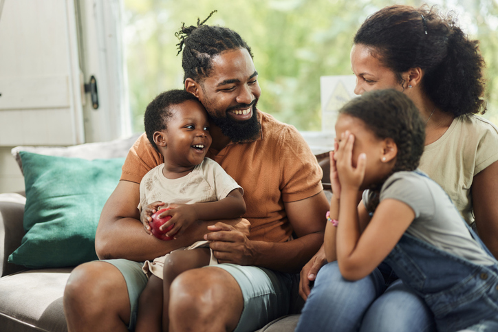 Happy black family talking on sofa at home.