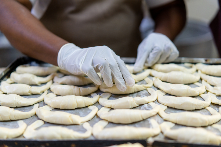 Close-up of woman baker preparing fresh croissants for baking