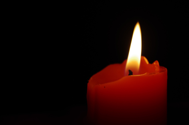 Close-up of a vibrant red candle burning brightly against a dark, mysterious background, symbolizing hope and contemplation