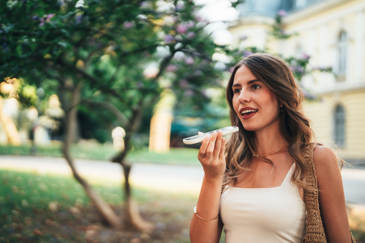 Young woman using AI Chatbot on smartphone outdoors