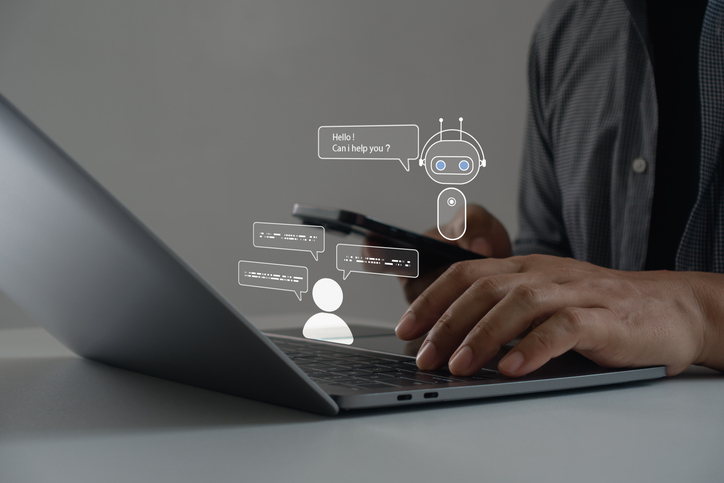 A person using a laptop and smartphone with virtual chatbot icons representing artificial intelligence and online communication technology for business support, digital marketing and customer service.